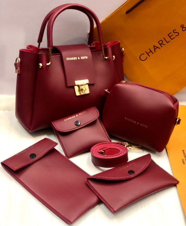 Red handbag set with matching pouches and wallet on a white background with 'Charles & Keith' branding.