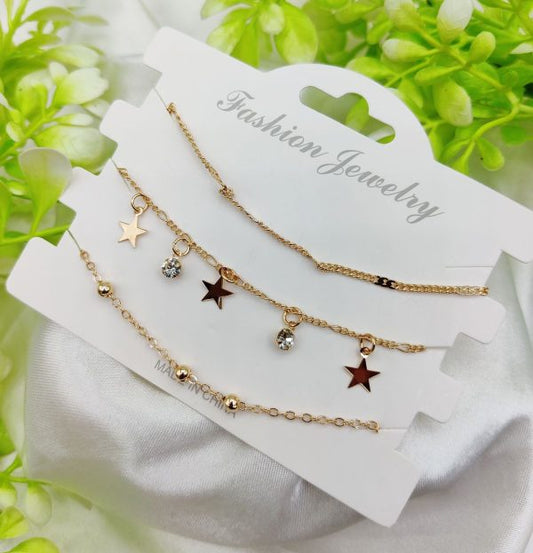 Set of gold necklaces with star and bead charms on a white card labeled 'Fashion Jewelry', with green leaves in the background.