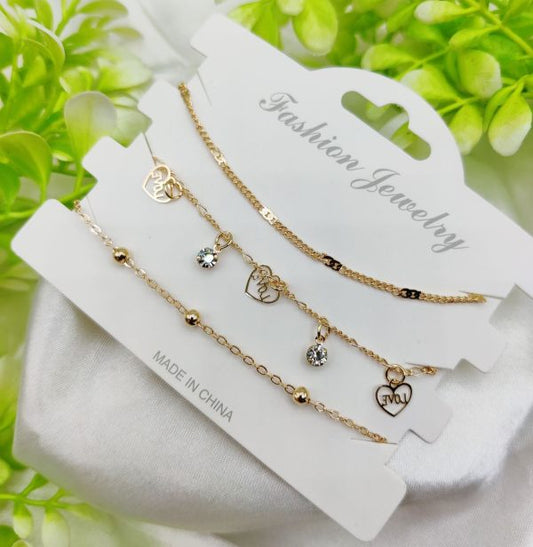 Set of gold necklaces with heart and diamond charms on a white card with 'Fashion Jewelry' text, against a green leafy background.