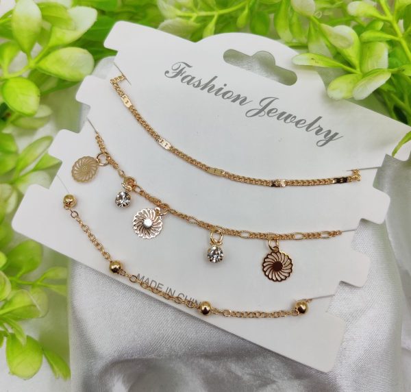 Gold necklace with Sun Burnt charms on a white card labeled 'Fashion Jewelry' against a green leafy background.